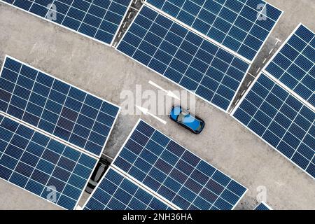 Luftaufnahme direkt über einem eigenständigen Parkplatz mit Solarpaneelen zum Aufladen von Elektroautos in einem innovativen Technologiekonzept Stockfoto