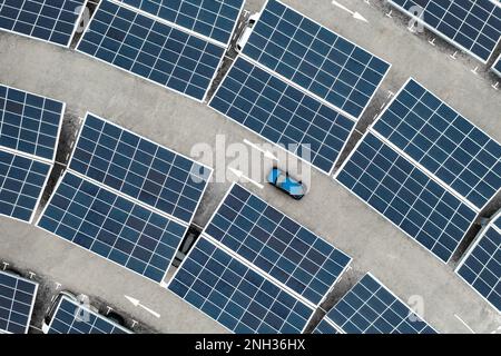 Luftaufnahme direkt über einem eigenständigen Parkplatz mit Solarpaneelen zum Aufladen von Elektroautos in einem innovativen Technologiekonzept Stockfoto