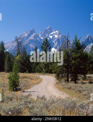 Gewundene Schotterstraße mit Grand Teton Mountains im Hintergrund Stockfoto