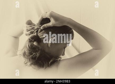 Rückansicht einer jungen Frau, die ihr Haar frisiert. Stockfoto