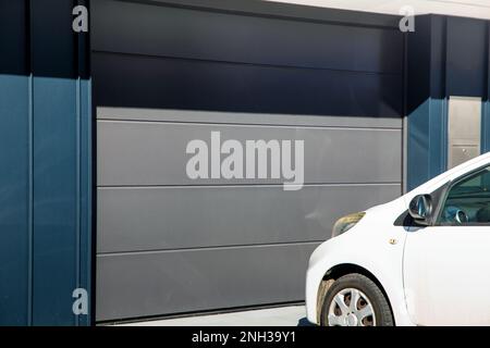 Modernes Garagentor (geteilte Tür) mit Auto davor geparkt Stockfoto