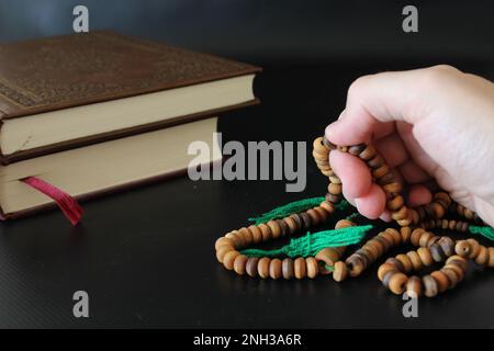 Die Hand der muslime betet mit Rosenkranz auf koranischem Hintergrund. islamischer Konsept Stockfoto