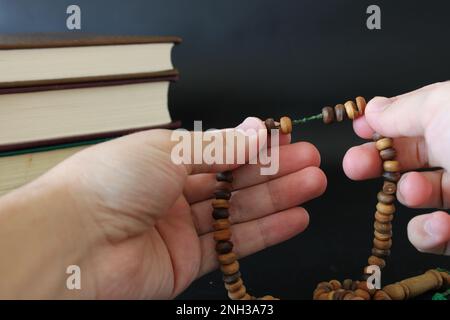 Die Hand der muslime betet mit Rosenkranz auf koranischem Hintergrund. islamischer Konsept Stockfoto