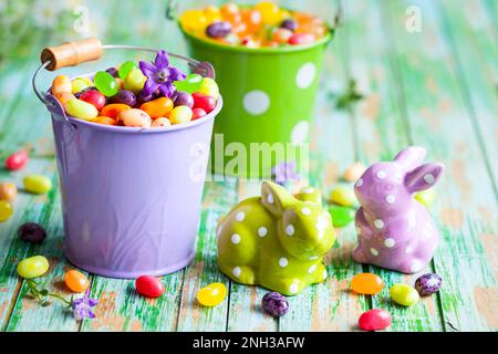 Osterkaninchen und Eimer mit Jelly Beans auf dem alten Holztisch Stockfoto