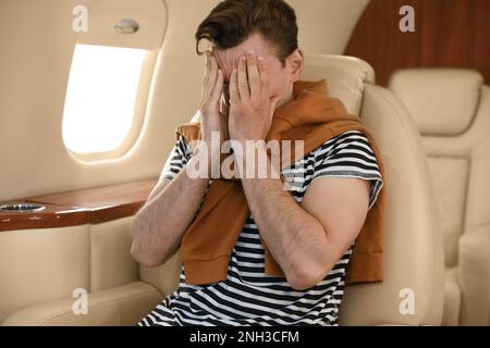 Junger Mann fühlt sich schlecht während des Fluges im Flugzeug Stockfoto