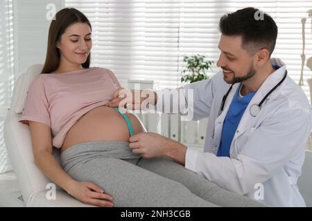 Der Arzt, der den Bauch einer schwangeren Frau mit Klebeband in der Klinik misst Stockfoto