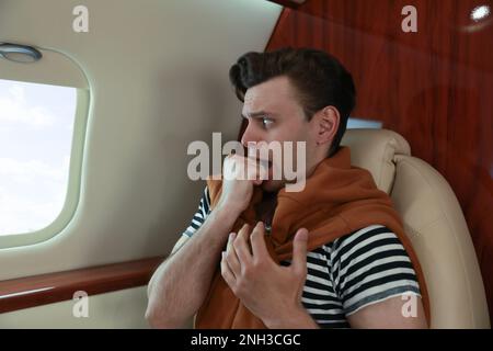 Nervöser junger Mann im Flugzeug. Aviophobie-Konzept Stockfoto