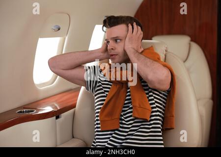 Nervöser junger Mann im Flugzeug. Aviophobie-Konzept Stockfoto