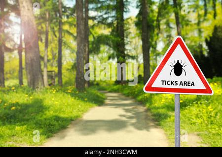 Warnschild Vorsicht vor Zecken im Wald an sonnigen Tagen Stockfoto