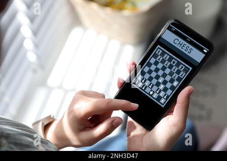 Frau, die online Schach auf Smartphone spielt, drinnen, Nahaufnahme Stockfoto