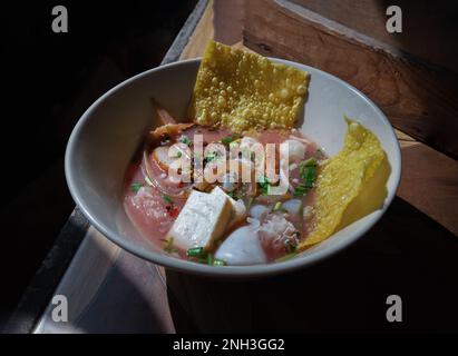 Yentafo Eiernudeln Suppe mit rosa Sauce und Fischbällchen, Garnelen, frischer Tintenfisch, frischer Tintenfisch, eingelegter Tintenfisch, Quallen, Tofu und gebratene Wontons mit Witz Stockfoto