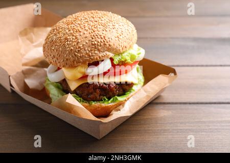 Köstlicher Burger in einer Pappschachtel auf einem Holztisch Stockfoto