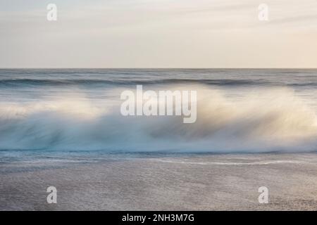 Absichtliche Kamerabewegung einer Welle, die am Strand von Worthing, West Sussex, Großbritannien, abstürzt Stockfoto