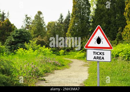 Warnschild Vorsicht vor Zecken im Wald an sonnigen Tagen Stockfoto