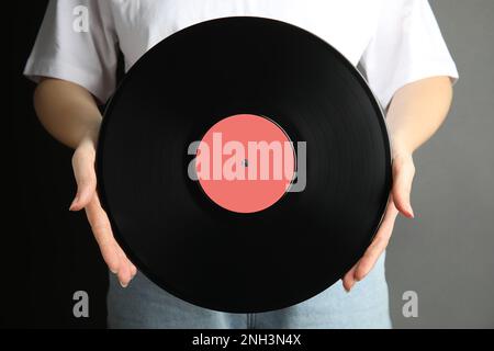 Eine Frau, die eine klassische Schallplatte auf grauem Hintergrund hält, Nahaufnahme Stockfoto