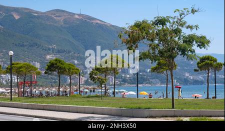 Promenade mit Sonnenanbetern entlang der Bucht von Vlorë im Sommer und der Ceraunianischen Berge im Hinterland von Vlora im Südwesten Albaniens Stockfoto