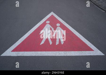 Dreieckiges Warnschild auf der gepflasterten Straße mit Fußgängern. Damit die Fahrer vorsichtig fahren und auf Fußgänger achten. Stockfoto