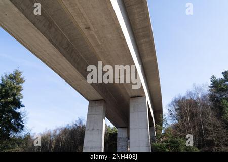 Große Betonbrücke von unten mit blauem Himmel an einem sonnigen Tag im Frühling Stockfoto