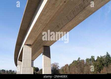 Große moderne Betonbrücke von unten in der Landschaft mit blauem sonnigen Himmel im Frühling Stockfoto