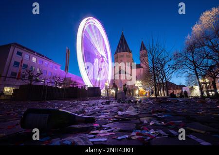 Mainz, Deutschland. 20. Februar 2023. Ein Riesenrad dreht sich nach der Shrove-Montags-Prozession vor der Kathedrale, während eine Flasche im Vordergrund liegt. Das Motto der Prozession lautete: "In Mainz steht Shrovetide voll und ganz für Frieden, Freiheit, Toleranz!" Aufgrund der Corona-Pandemie fand sie zum ersten Mal seit zwei Jahren statt. Kredit: Sebastian Christoph Gollnow/dpa/Alamy Live News Stockfoto