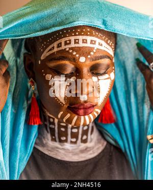 Eine Frau aus Afrika trägt Kopfschmuck und Stammesmalerei Stockfoto