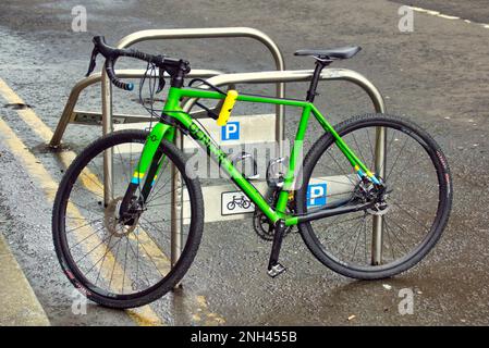 Grünes Fahrrad auf einem Straßenradständer geparkt Stockfoto