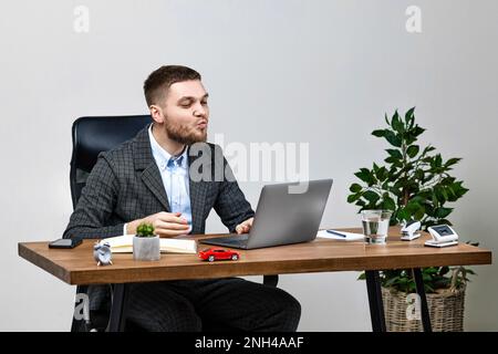 Mann sitzt auf einem Stuhl am Tisch und ruht sich aus, benutzt Laptop Stockfoto