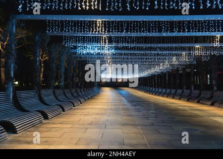 Russland, Krasnodar - 04. Januar 2023: Nachtbeleuchtung des Parks Galicki. Pavillon mit blauer Girlande und Bänken zur Erholung. Keine Leiche Stockfoto