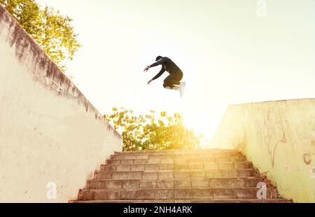 Ein Mann, der Parkour macht und Mauern überspringt. Ein lateinischer Mann, der Parkour macht, Mauern springt, ein kleiner Winkel von Mann, der Parkour bei Sonnenuntergang macht Stockfoto
