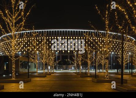 Russland, Krasnodar - 04. Januar 2023: Stadion des Fußballvereins Krasnodar bei Nacht. Beleuchtung an der Fassade und Girlanden an den Bäumen Stockfoto