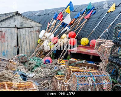 Bildfoto kommerzieller Fischereihilfen, die in Küstenhütten an der Küste von Northumberland, Northumberland, England, Großbritannien gelagert werden - Markierungsbojen, Netze, Seile, Hummertöpfe und Krabbenkrebse. Stockfoto