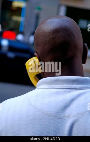 Der farbige New Yorker, der mit einem gelben Handapparat telefoniert, New York City, USA Stockfoto