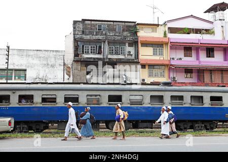 Muslimische Männer gehen vor einem Zug am Bahnhof in Trang Town, Trang Province, Südthailand, Thailand Stockfoto