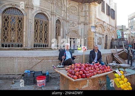 Ein ägyptischer Mann, der an einem Obststand Shisha oder Wasserpfeife raucht, in der Altstadt, in Kairo, Ägypten Stockfoto