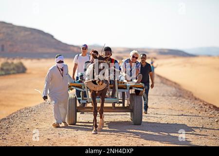 Ägyptische Männer und Touristen auf einem Pferdewagen in der nubischen Wüste, Wadi Al-Sebua, Assuan, Ägypten Stockfoto