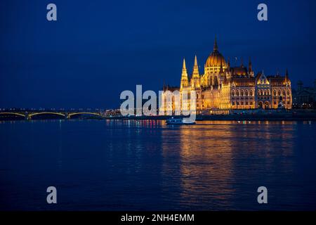 Beleuchtetes ungarisches Parlamentsgebäude und Margit Hidd, Margaretenbrücke bei Nacht mit Reflexion auf die Donau, Budapest, Ungarn. Stockfoto