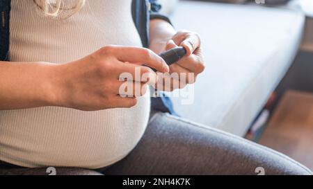 Nahaufnahme der Schwangeren mit dem Lanzengerät zur Blutzuckermessung Stockfoto