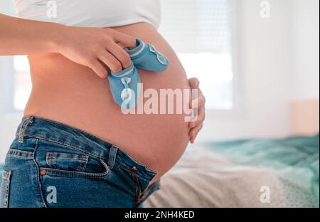 Schwangere Frau hält blaue Schuhe für ihr neues Baby Stockfoto