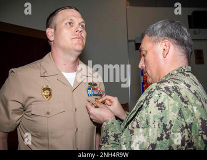 Cmdr. Douglas Kennedy, Stabschef des Kommandanten, Fleet Activities Sasebo (CFAS), Pins LT. j.g. Zachery Bixby, Assistant Security Officer der CFAS, mit dem Abzeichen des Navy Security Force Officers während einer Qualifikationszeremonie am 13. Dezember 2022 bei der CFAS. Seit 75 Jahren stellt die CFAS Basiseinrichtungen und -Dienste bereit, wartet und betreibt diese, um die US- und alliierten Streitkräfte zu unterstützen und gleichzeitig ihre Familien und die Gemeinschaft optimal zu unterstützen. Stockfoto