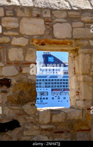 Kusadasi, Türkei - Mai 2022: Seite des norwegischen Kreuzfahrtschiffs Norwegian Cruise Lines, Norwegische Jade, durch ein Fenster mit Blick auf die alte Festung der Stadt Stockfoto