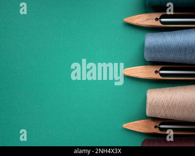 Hölzerne Shuttles für Handstühle und Zapfen mit Garn in neutralen Farben, Kopierraum. Konzept von Webwerkzeugen Stockfoto