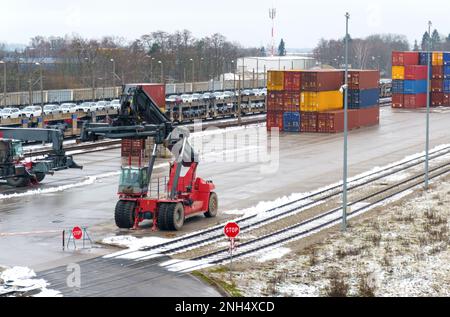 Der Lader steht auf der Baustelle und wartet auf das Entladen oder Laden von Frachtcontainern an der Station. Die Eisenbahn wartet auf das Warentransportterminal. Stockfoto