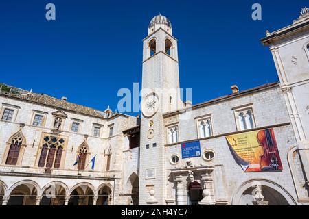 Uhrenturm (Gradski Zvonik) und Sponza-Palast auf dem Loggia-Platz, mit dem kleinen Brunnen von Onofrio auf der rechten Seite, in der Altstadt von Dubrovnik in Kroatien Stockfoto