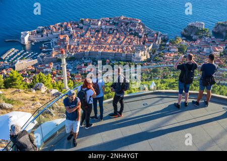 Besucher auf der Aussichtsplattform an der oberen Seilbahnstation mit Blick auf die alte ummauerte Stadt Dubrovnik an der dalmatinischen Küste Kroatiens Stockfoto