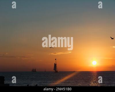 Beobachten Sie die Segelboote vom Mallory Square in Key West Florida, während die Sonne über dem Ozean untergeht. Stockfoto