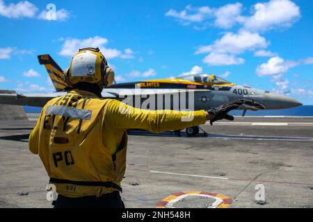 PACIFIC OCEAN (21. Juni 2022)) Aviation Boatswain’s Mate (Handling) 3. Class Luis Placencia aus Oakland, Kalifornien, leitet ein F/A-18E Super Hornet, das den „Vigilantes“ der Streikkampfstaffel (VFA) 151 auf dem Cockpit des Flugzeugträgers der Nimitz-Klasse USS Abraham Lincoln (CVN 72) zugewiesen ist. Abraham Lincoln Strike Group führt Routineeinsätze in der US-3.-Flotte durch. Stockfoto