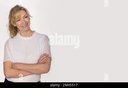 Attraktives, lächelndes weibliches Studioporträt mittleren Alters auf weißem Hintergrund Stockfoto