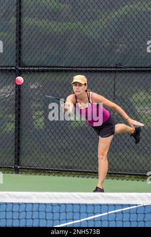 Ein Pickleball-Spieler serviert den Ball im Sommer auf einem Pickleball-Platz in der Vorstadt. Stockfoto