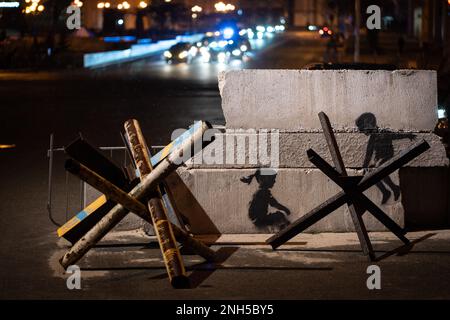 Kiew, Ukraine. 20. Februar 2023. Kiew, Ukraine - 20. Februar 2023: Banksys mögliches Graffiti auf Betonplatten in Kiews Maidan Nezalezhnosti (Unabhängigkeitsplatz): Zwei Kinder, als schaukelten sie, wie eine Wippe, auf einer Panzerabwehr. (Foto: Kish Kim/Sipa USA) *** Korea out *** Kredit: SIPA USA/Alamy Live News Stockfoto