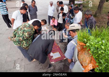 Eine Gruppe von Männern versammelte sich, um ein chinesisches Schachspiel in einer alten Straße in der Stadt Jianshui, Provinz Yunnan, China, zu sehen Stockfoto